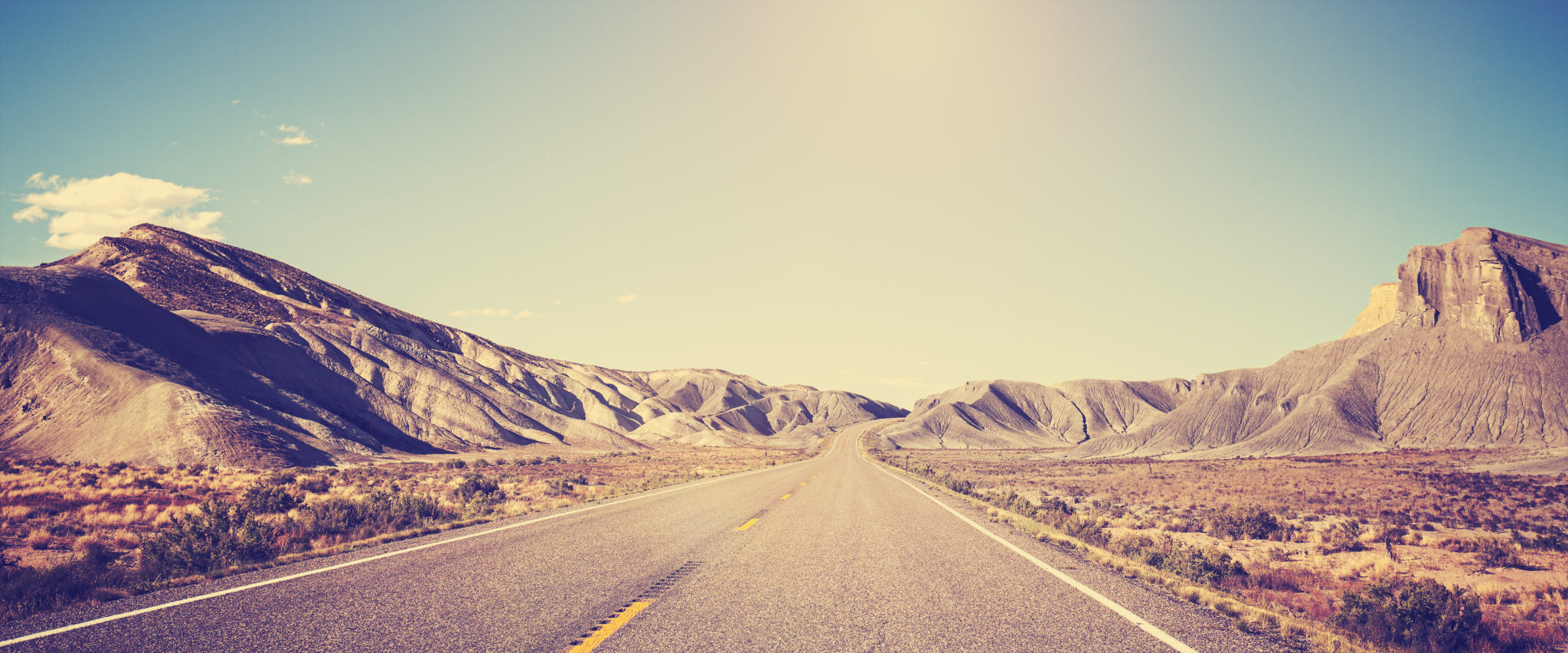 Vintage toned panoramic photo of desert road, Utah, USA.